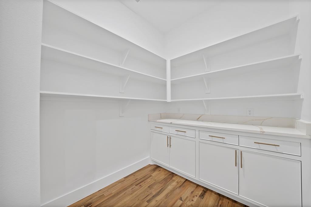 710 Gibson Road Waxahachie, TX 75165 - Photo 15 of 36 This pantry features extensive white shelving, white base cabinets with gold-toned hardware, and a light-toned countertop with veining