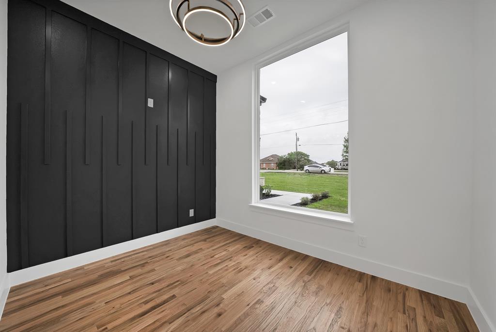 710 Gibson Road Waxahachie, TX 75165 - Photo 25 of 36 This room features hardwood flooring, a statement accent wall with vertical paneling, and a large window providing views of the outdoors