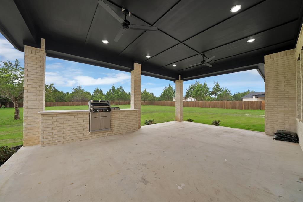 710 Gibson Road Waxahachie, TX 75165 - Photo 30 of 36 The property features an expansive outdoor patio with a built-in grill, overhead lighting, and two ceiling fans