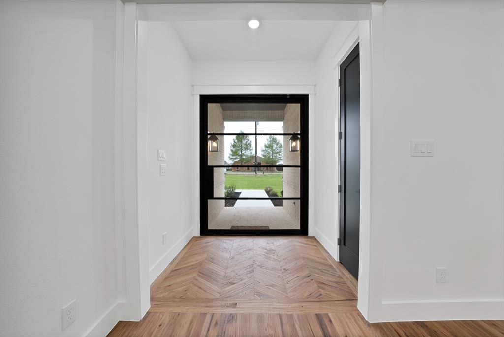 710 Gibson Road Waxahachie, TX 75165 - Photo 3 of 36 Entrance featuring a dark framed glass door, herringbone pattern wood flooring, and a dark interior door
