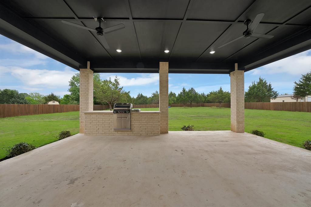 710 Gibson Road Waxahachie, TX 75165 - Photo 31 of 36 The property features an expansive covered patio with a concrete surface, equipped with ceiling fans and recessed lighting