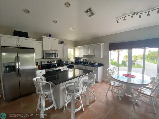 a kitchen with a dining table chairs and refrigerator