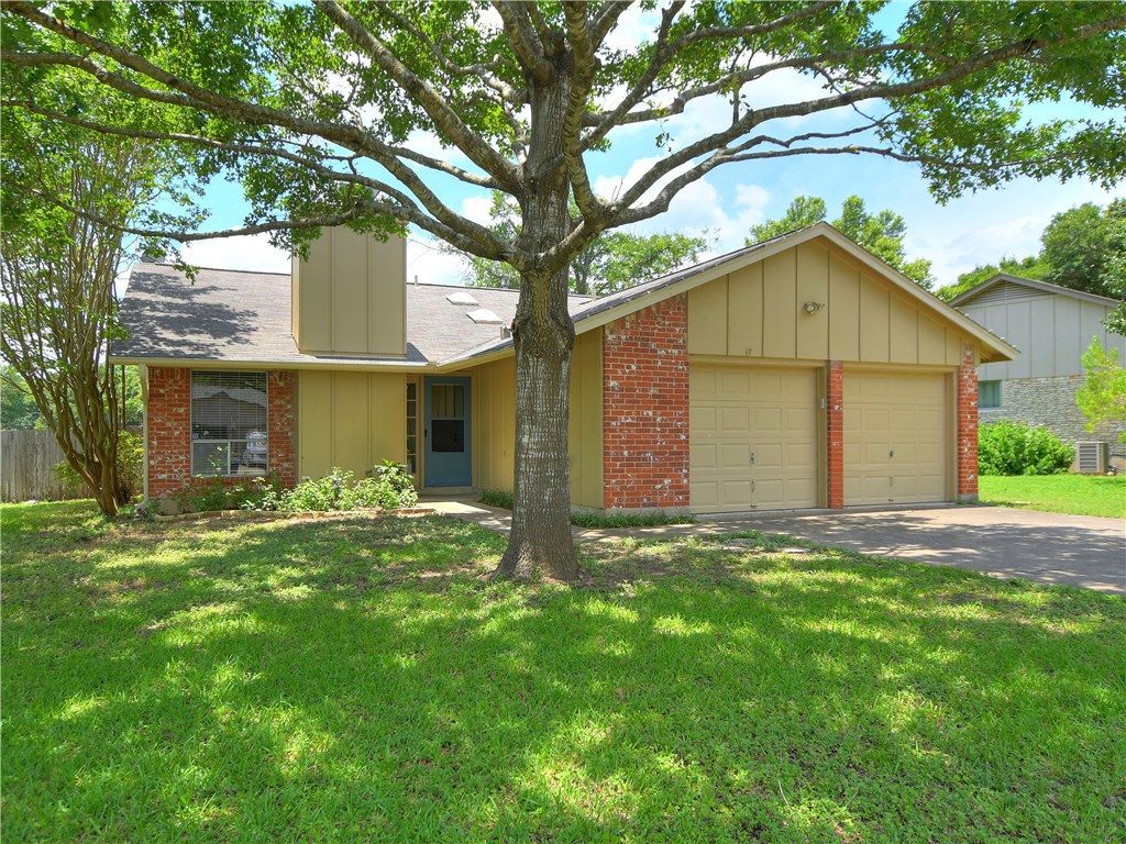 a view of a yard in front of a house with large tree