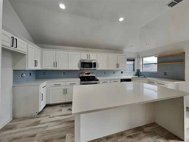 a kitchen with stainless steel appliances granite countertop a refrigerator sink and white cabinets