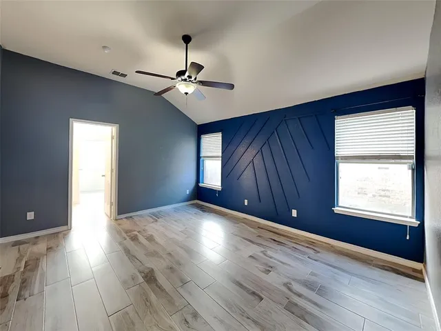 a view of an empty room with a window and wooden floor