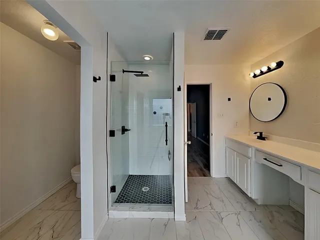a large bathroom with a glass shower door and a sink