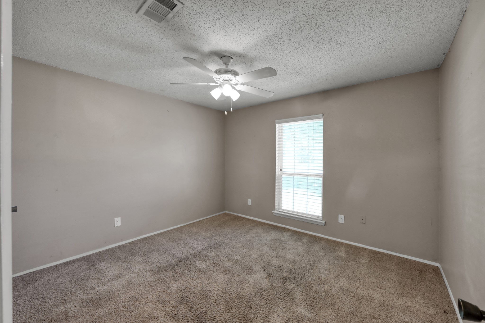 12015 Fallbrook Drive Houston, TX 77065 - Photo 20 of 29 The room is a simple, cozy space with neutral-colored walls and carpet flooring, featuring a ceiling fan and a window with blinds for natural light.