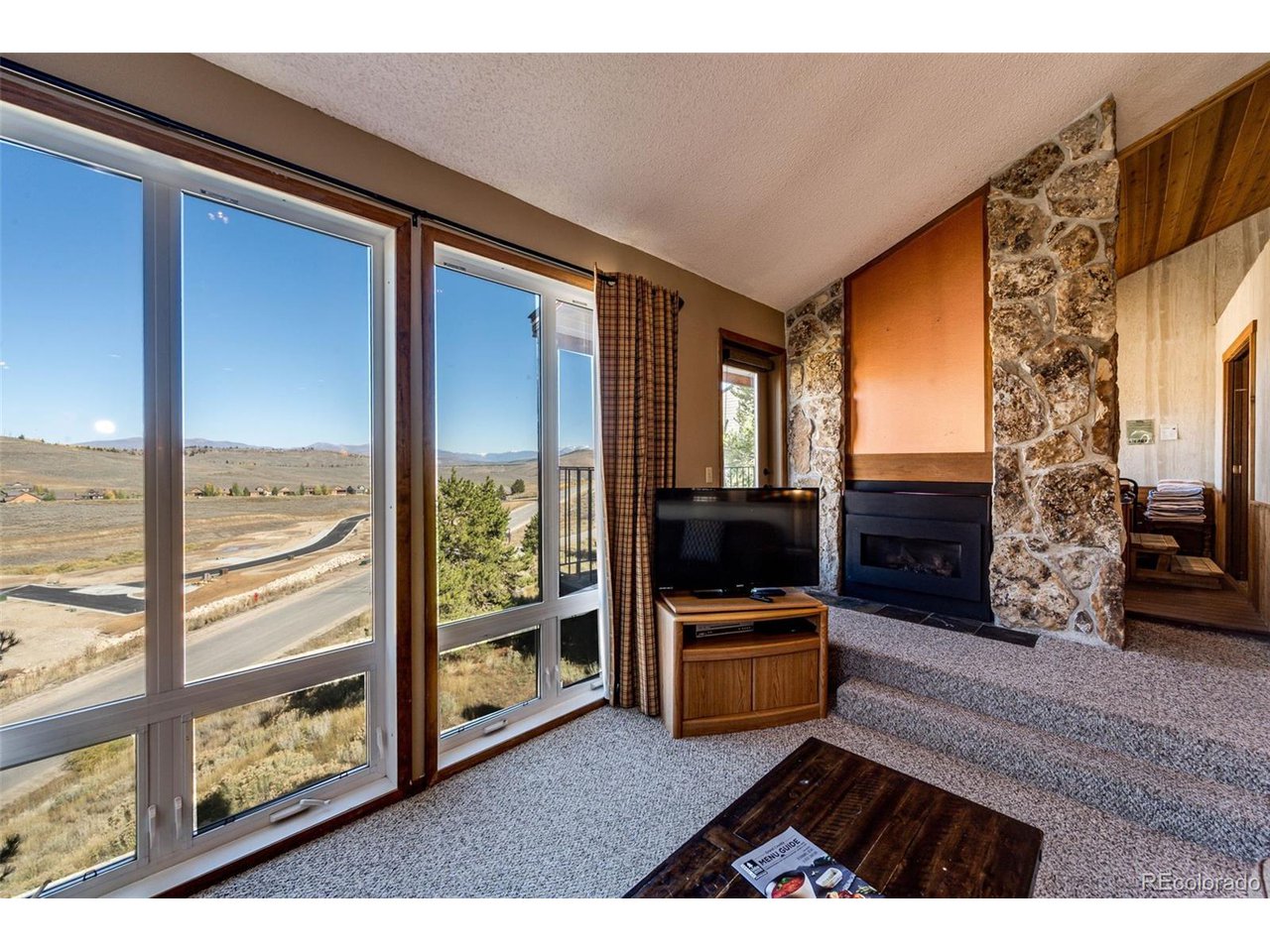 a living room with couches a flat tv screen and a fireplace