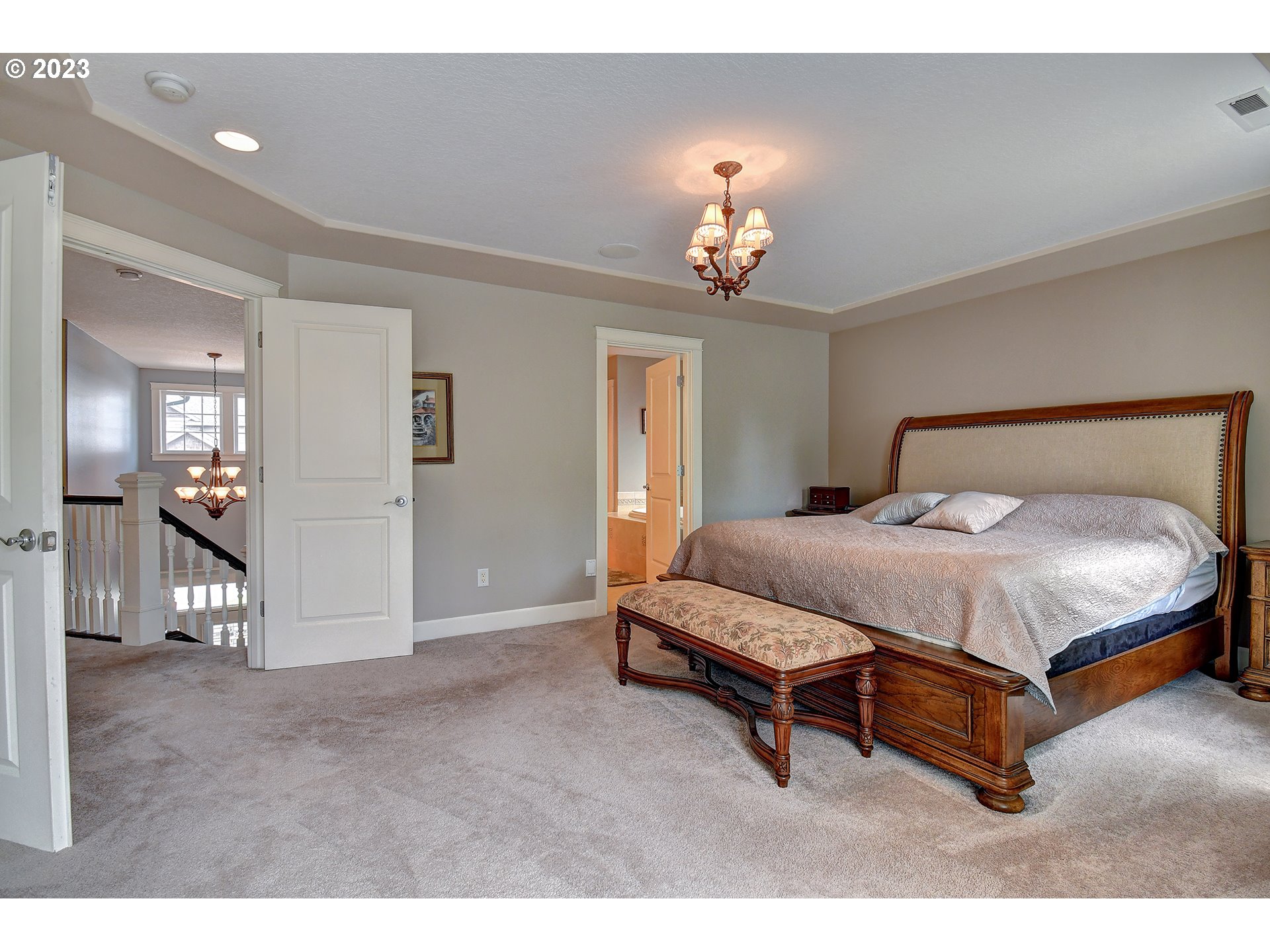 907 North 7th Circle Ridgefield, WA 98642 - Photo 19 of 47 a spacious bedroom with a bed and a chandelier