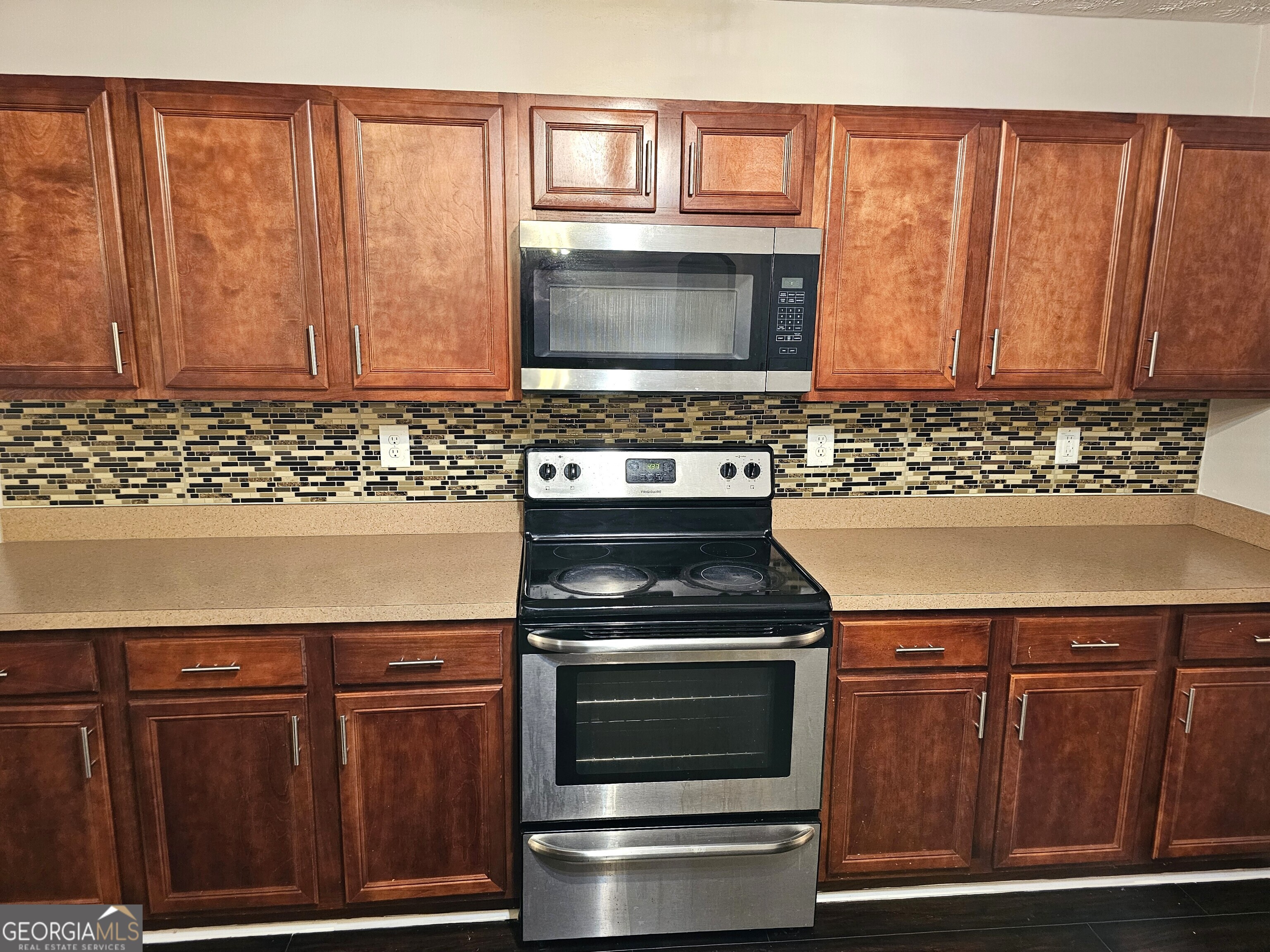11223 Genova Terrace Hampton, GA 30228 - Photo 13 of 26 a kitchen with granite countertop a stove top oven cabinetry a sink and a window
