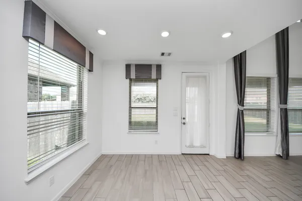 a view of an empty room with wooden floor and a window