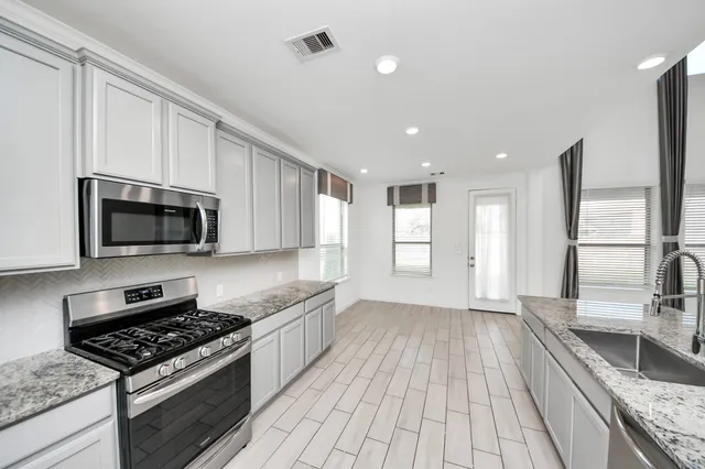 a kitchen with stainless steel appliances granite countertop a stove a sink and a microwave