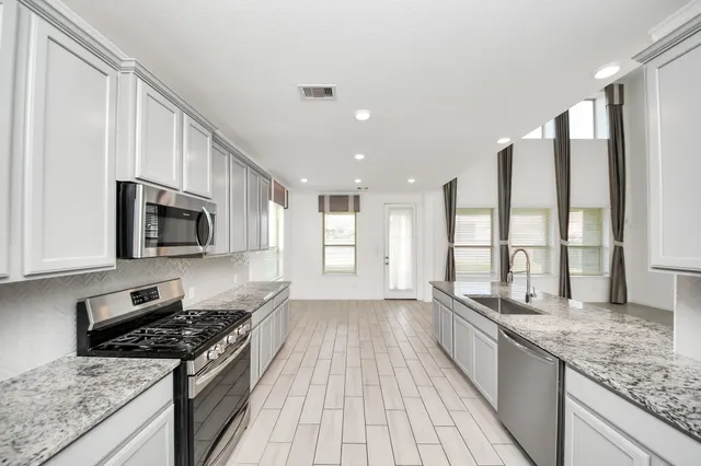 a large kitchen with stainless steel appliances granite countertop a stove and a sink