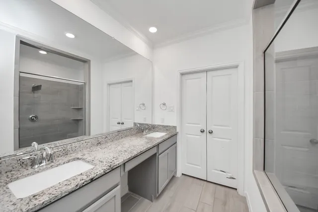 a bathroom with a granite countertop sink two mirror and shower