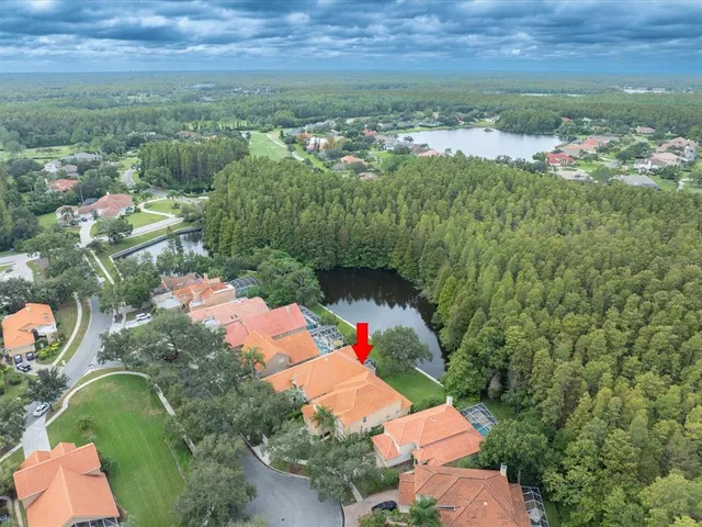 a view of a house next to a big yard and large trees