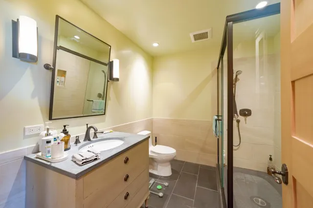 a bathroom with a shower sink vanity mirror and toilet