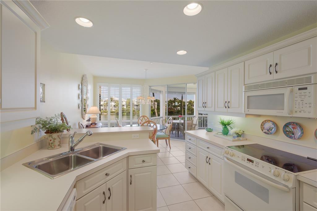 760 Seaboard Line Lane Boca Grande, FL 33921 - Photo 11 of 71 a kitchen with a sink dishwasher stove and white cabinets with wooden floor