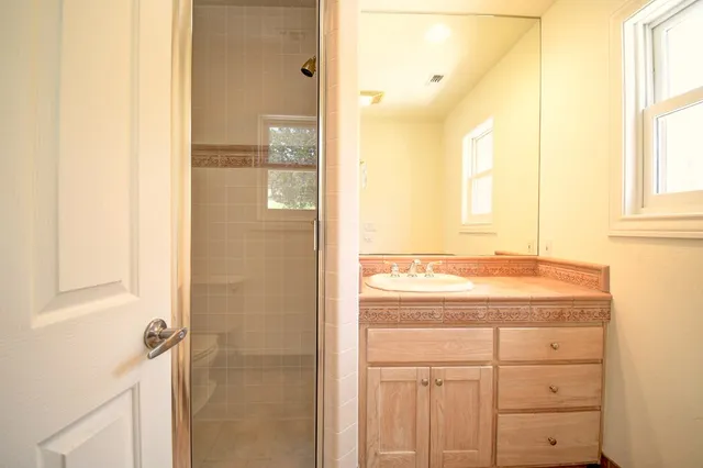 a bathroom with a granite countertop sink a mirror and a shower