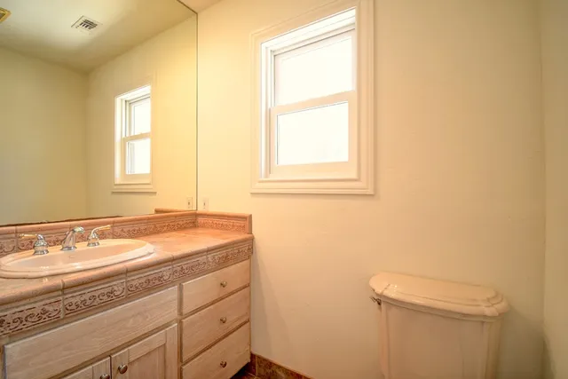 a bathroom with a granite countertop sink a toilet and a window