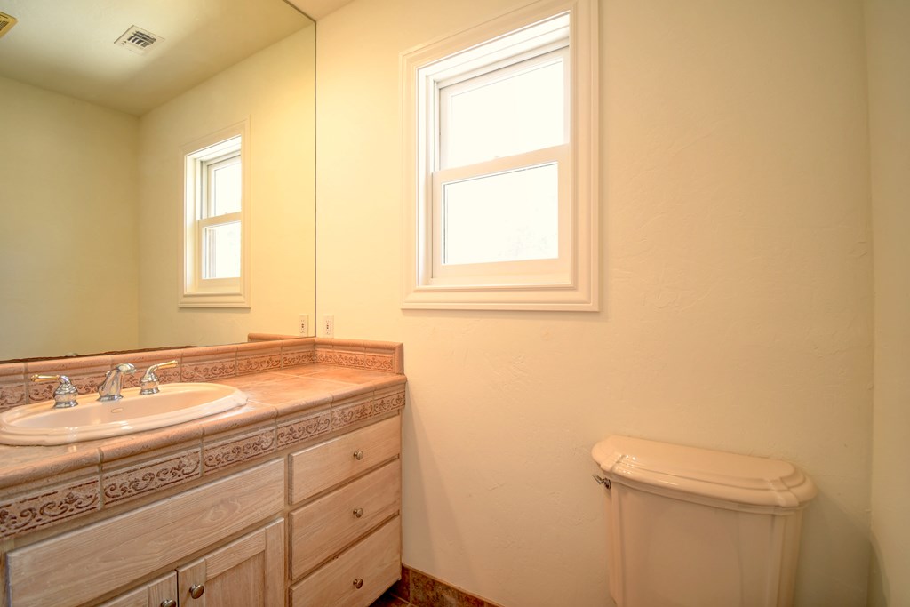 155 B Nimitz Road Kerrville, TX 78028 - Photo 15 of 30 a bathroom with a granite countertop sink a toilet and a window