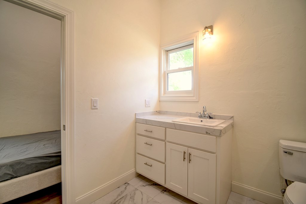 155 B Nimitz Road Kerrville, TX 78028 - Photo 22 of 30 a bathroom with a granite countertop sink a toilet and with a window