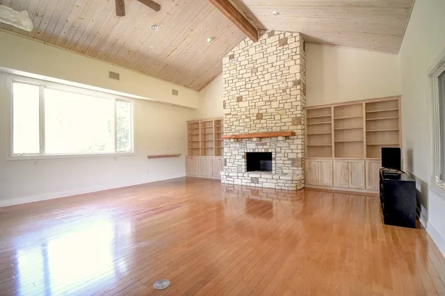 a view of empty room with wooden floor and fireplace