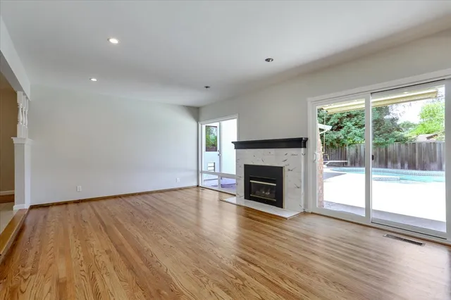 an empty room with wooden floor fireplace and windows
