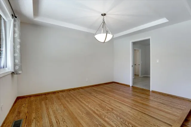 a view of an empty room with wooden floor and window