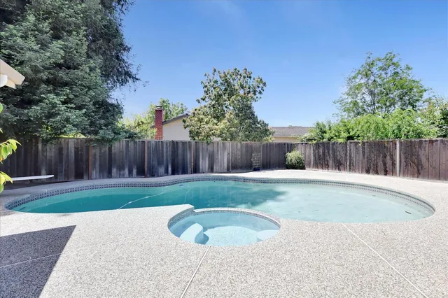 a view of a backyard with swimming pool and wooden fence