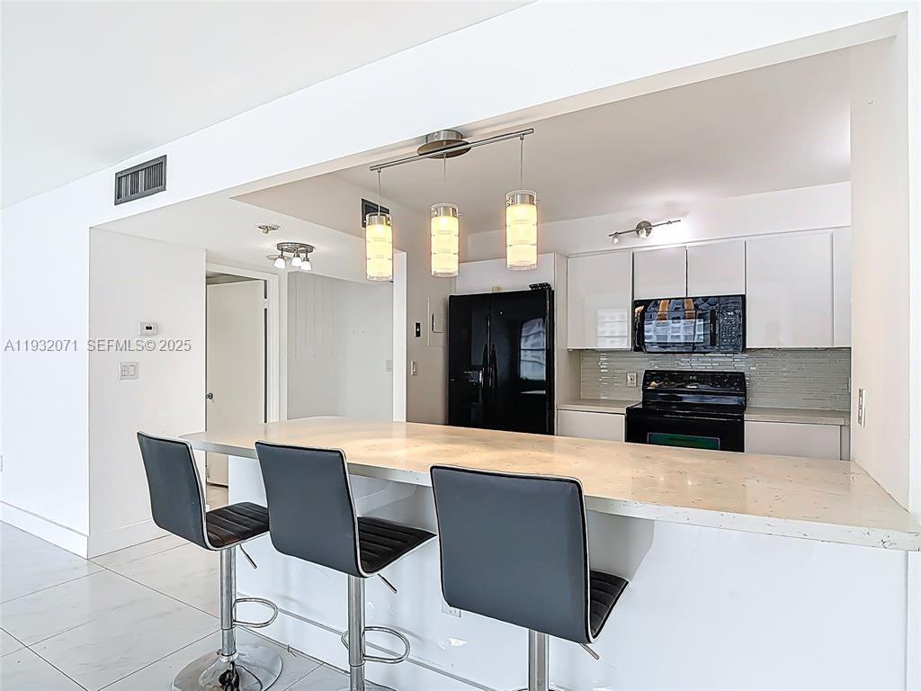 2801 Northeast 183rd Street, Unit 1504W Aventura, FL 33160 - Photo 26 of 57 a large kitchen with stainless steel appliances kitchen island granite countertop a refrigerator and microwave