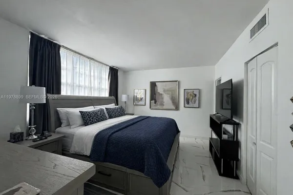 a bedroom with a bed and a flat tv screen on the dresser