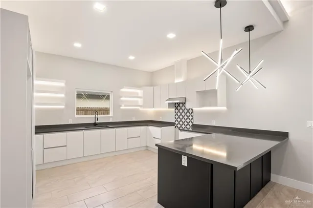 a kitchen with stainless steel appliances granite countertop a sink a stove and a wooden floor