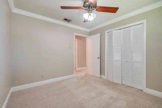 an empty room with a chandelier fan and closet area