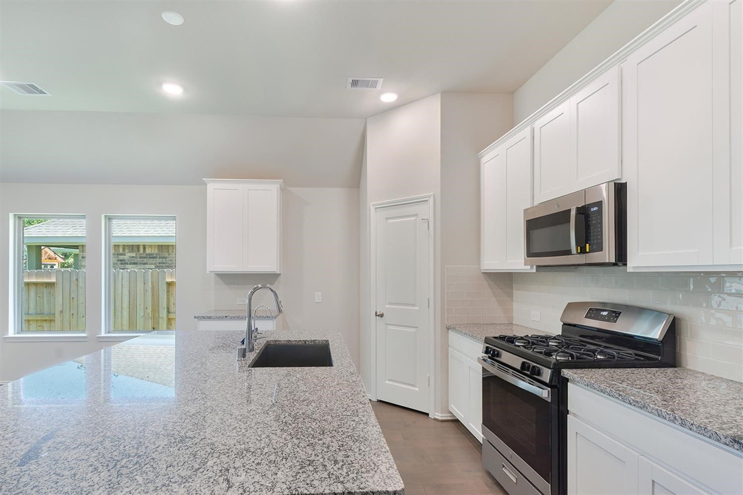 553 Timber Voyage Court Conroe, TX 77304 - Photo 9 of 31 a kitchen with stainless steel appliances granite countertop a stove a sink and a microwave