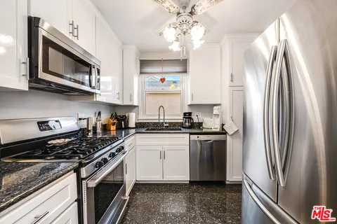 a kitchen with stainless steel appliances granite countertop a stove a sink and a refrigerator