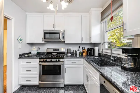 a kitchen with granite countertop white cabinets and white appliances