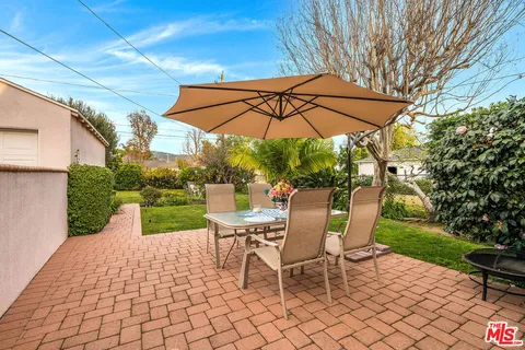 a view of a backyard with table and chairs under an umbrella