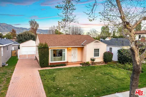 a front view of a house with a yard and potted plants