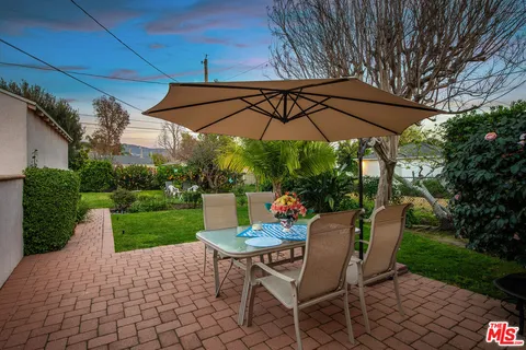 a view of a backyard with table and chairs under an umbrella