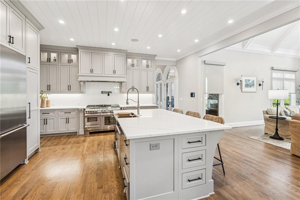 3030 Wills Mill Road Cumming, GA 30041 - Photo 4 of 71 a large kitchen with kitchen island a stove a sink a refrigerator and white cabinets with wooden floor