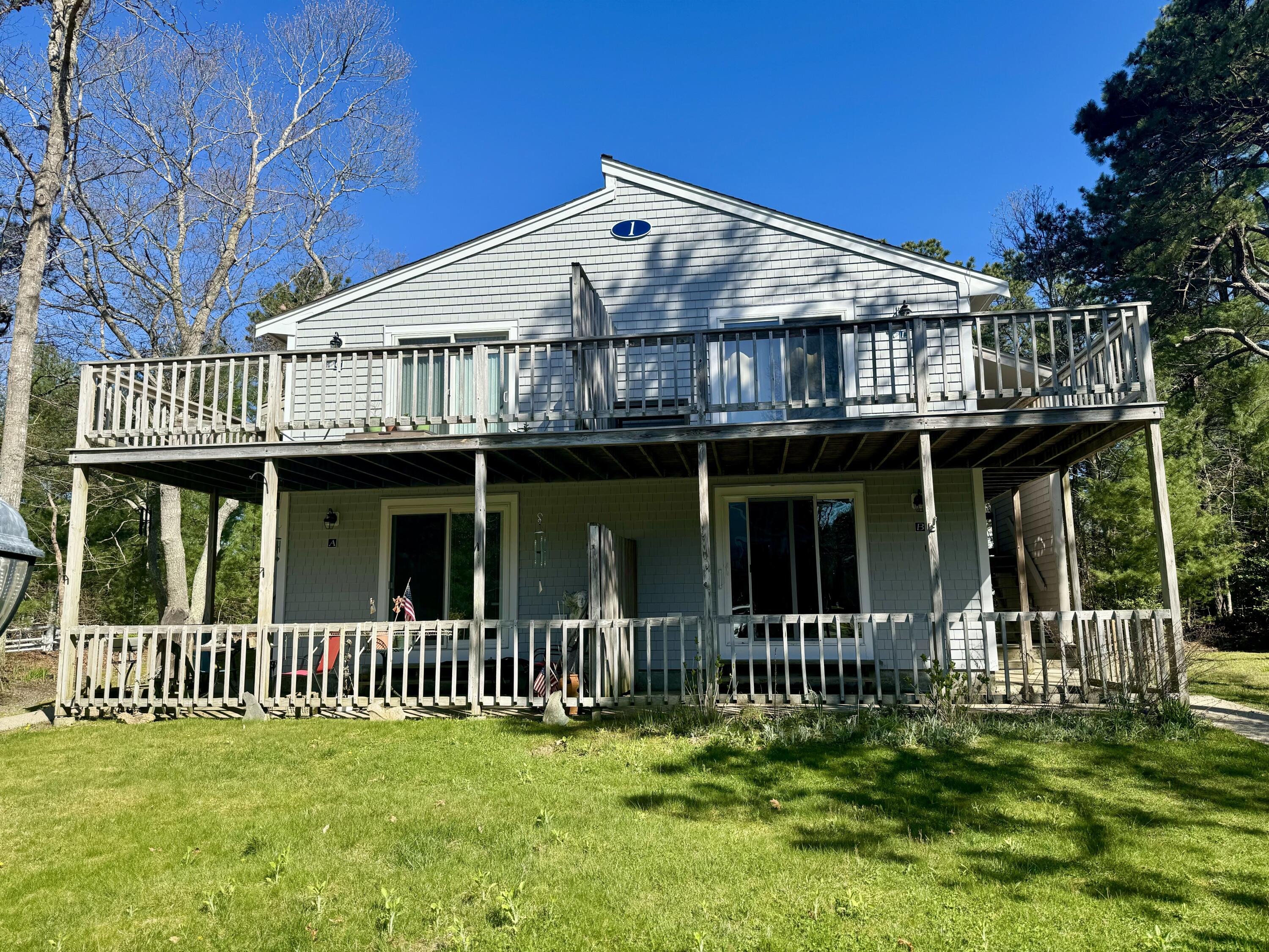 70 Cape Drive, Unit 1B Mashpee, MA 02649 - Photo 2 of 13 a view of a house with a small yard and deck