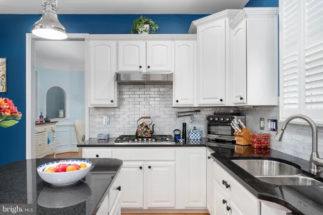 a kitchen with white cabinets and sink