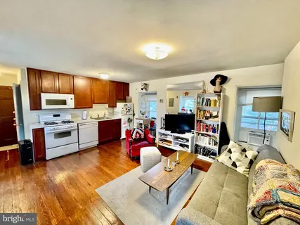 a living room with furniture kitchen view and a wooden floor