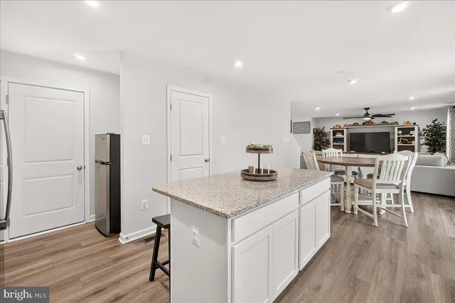 a kitchen with stainless steel appliances kitchen island granite countertop a table chairs stove and microwave