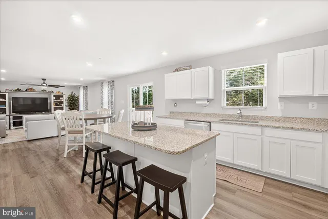 a kitchen with stainless steel appliances granite countertop a stove a sink dishwasher a microwave oven and a dining table with wooden floor