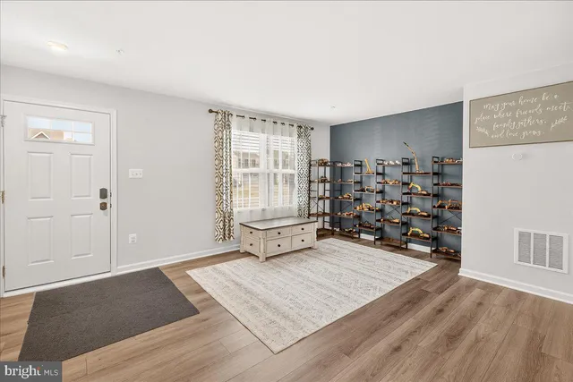 a view of an empty room with wooden floor and windows