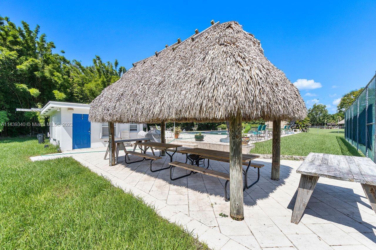 18201 Spring Road Southwest Ranches, FL 33331 - Photo 20 of 29 a view of a patio with couches table and chairs under an umbrella with a fire pit