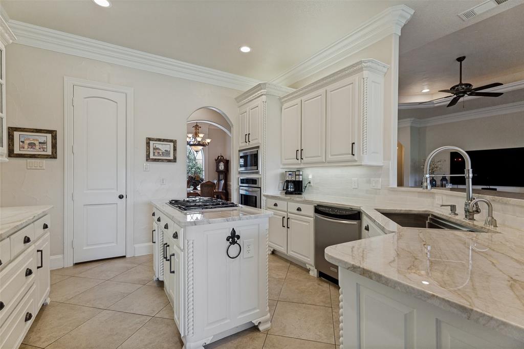 229 Arbor Lane Haslet, TX 76052 - Photo 10 of 34 Gourmet kitchen featuring a central island with built-in cooktop, extensive white cabinetry, light-toned stone countertops, and tile flooring