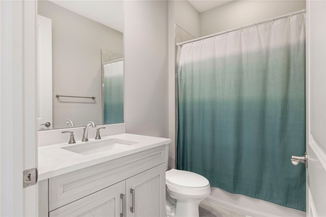 7203 33rd Square Vero Beach, FL 32967 - Photo 14 of 28 a bathroom with a sink a toilet a mirror and shower curtain