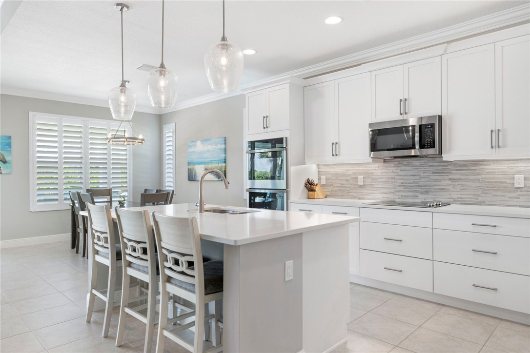 7203 33rd Square Vero Beach, FL 32967 - Photo 4 of 28 a large kitchen with kitchen island white cabinets and stainless steel appliances